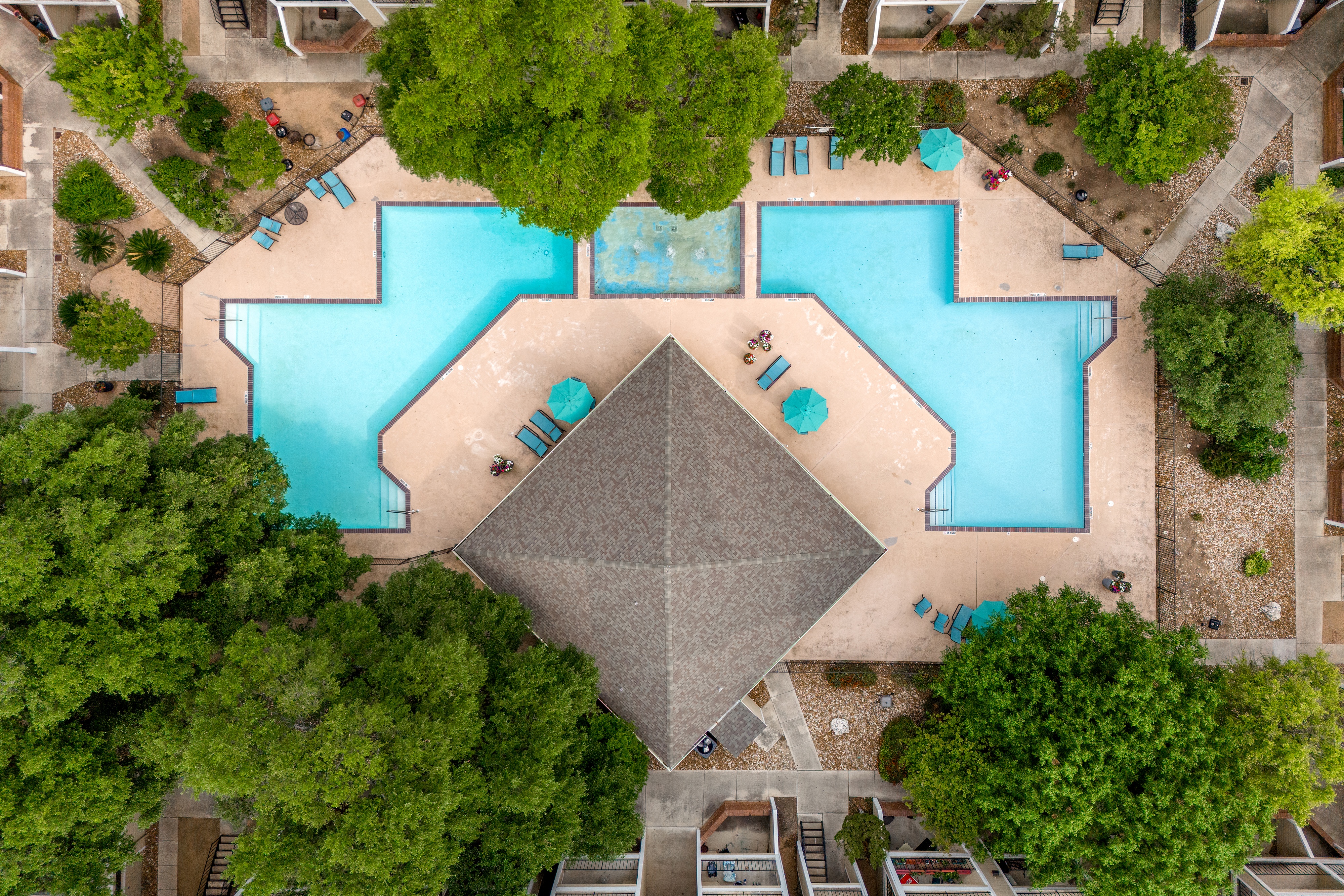 A swimming pool surrounded by trees and a pyramid-shaped structure in the middle.